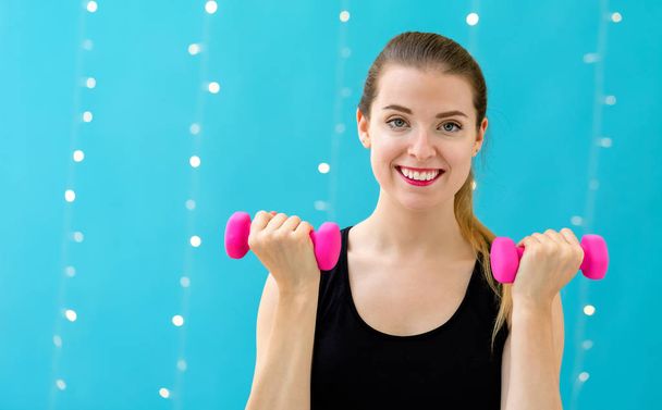 Young fit woman with dumbbells - 写真・画像