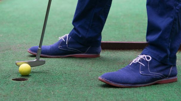 the last blow in the golf hole, close-up, stick and blue boots - Foto, afbeelding