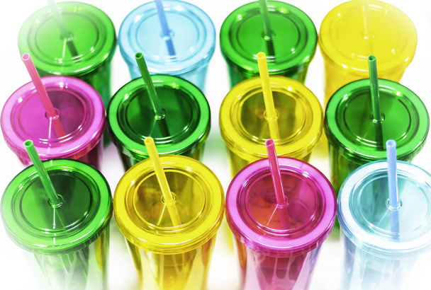 Πολύχρωμα πλαστικά ποτήρια με σωλήνα πρωτογενούς φόντο - Φωτογραφία, εικόνα