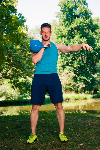 Fitness man doing kettlebell swing exercise in nature - Fotografie, Obrázek