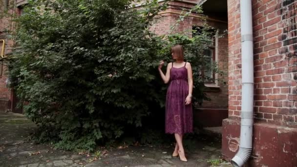 Heel mooi meisje poseren in de oude binnenplaats van bakstenen huizen. - Video