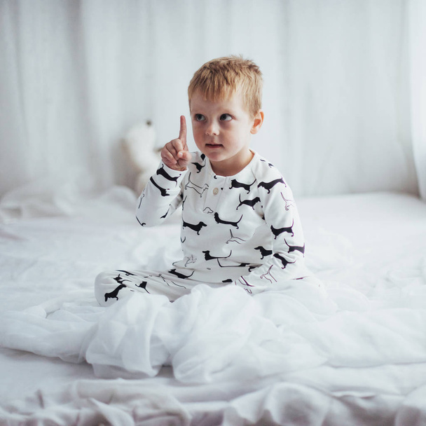 Child in soft warm pajama playing in bed - Fotó, kép