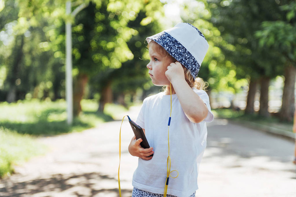 Cute girl listening to music with headphones outdoors. - Фото, зображення