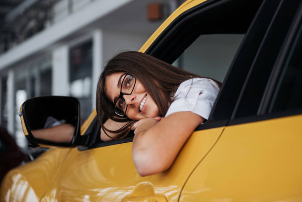 Молода жінка в її новій машині посміхається
. - Фото, зображення