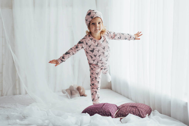 Lapsi pehmeässä lämmin pyjama leikkii sängyssä
 - Valokuva, kuva