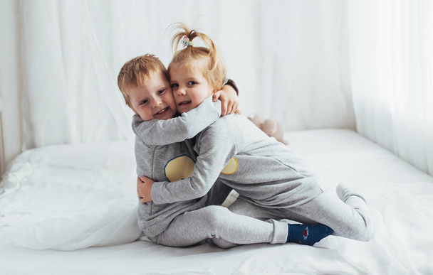 Children in soft warm pajamas playing in bed - Valokuva, kuva