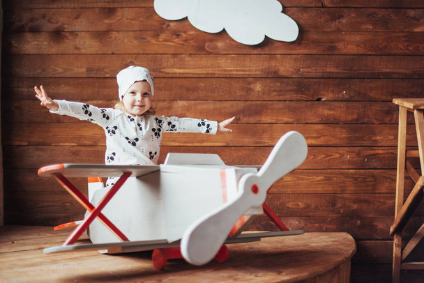 Счастливый ребенок играет с деревянным самолетом против. Детство. Фантазия, воображение. Праздник
 - Фото, изображение