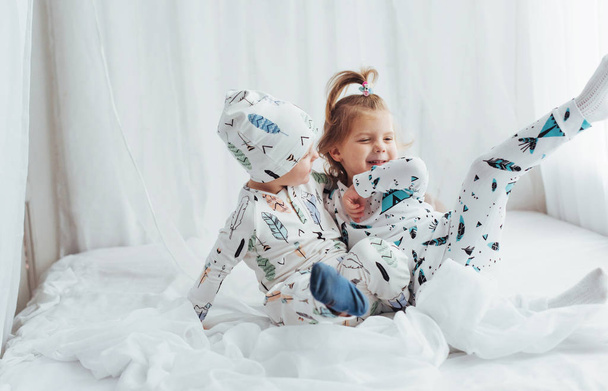 Niños en pijama suave y cálido jugando en la cama
 - Foto, imagen