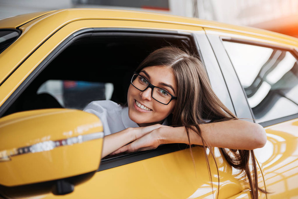 Young woman in her new car smiling. - Foto, afbeelding