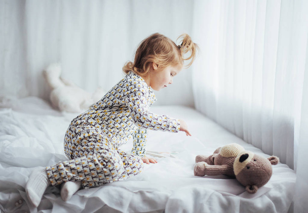 Child in soft warm pajama playing in bed - Foto, Imagen