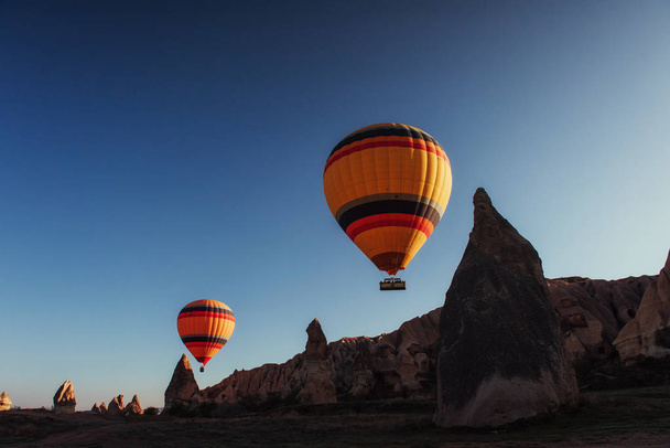 Heißluftballon fliegt über Felslandschaft in Kappadokien Türkei. Tal, Schlucht, Hügel, gelegen zwischen den vulkanischen Bergen im Goreme-Nationalpark. - Foto, Bild