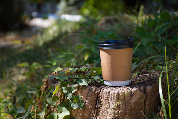 Paper cup of coffee  on a stump in the background of green foliage - Fotoğraf, Görsel