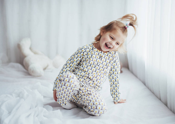 Παιδί σε μαλακό ζεστό pajama παίζει στο κρεβάτι - Φωτογραφία, εικόνα