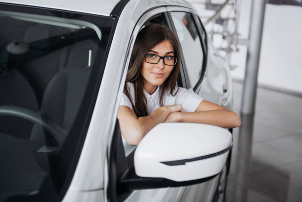 Arabanın ön koltuğunda kameraya bakarak çekici genç beyaz bir kadın - Fotoğraf, Görsel