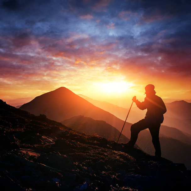 Счастливый человек, стоящий на скале на закате
. - Фото, изображение