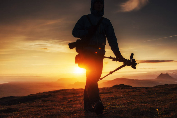 Ευτυχισμένος ο άνθρωπος που στέκεται σε ένα βράχο στο ηλιοβασίλεμα. - Φωτογραφία, εικόνα