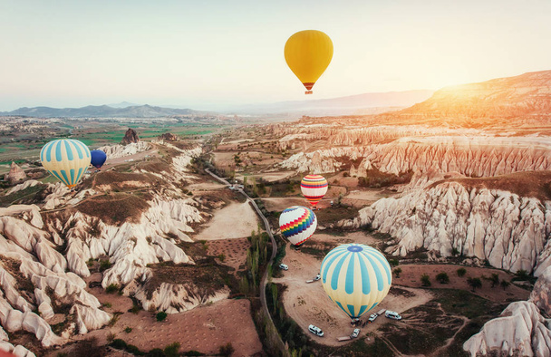 Colorful hot air balloons flying over Red valley at Cappadocia, Anatolia, Turkey. Volcanic mountains in Goreme national park. - Fotografie, Obrázek
