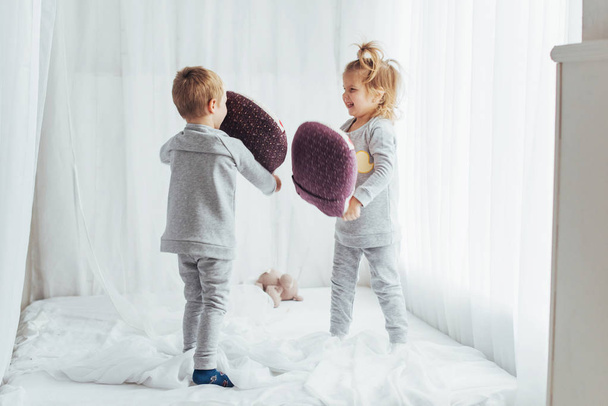 Children in soft warm pajamas playing in bed - Zdjęcie, obraz