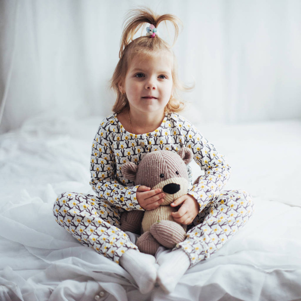 Child in soft warm pajama playing in bed - Фото, изображение