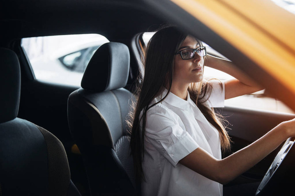 attractive young Caucasian woman looking at the camera from the front seat of the car - Photo, Image