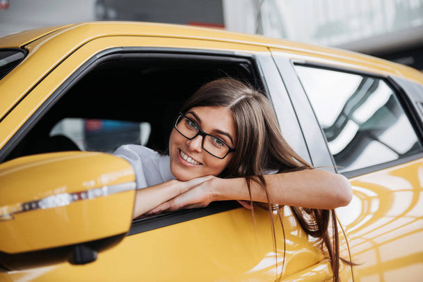 Young woman in her new car smiling. - Valokuva, kuva