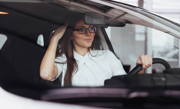 attractive young Caucasian woman looking at the camera from the front seat of the car - Foto, Imagem