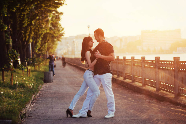 young couple dancing tango on the embankment of the river at sunset - Fotoğraf, Görsel