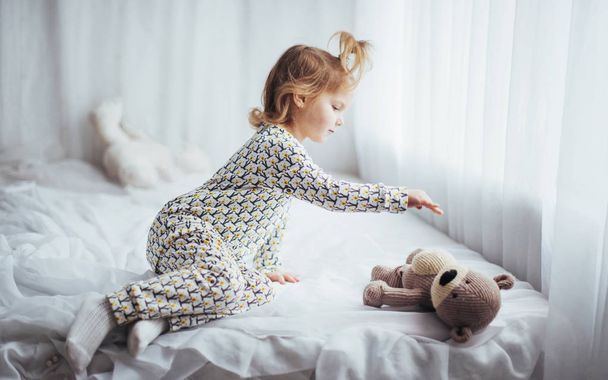Child in soft warm pajama playing in bed - Fotó, kép