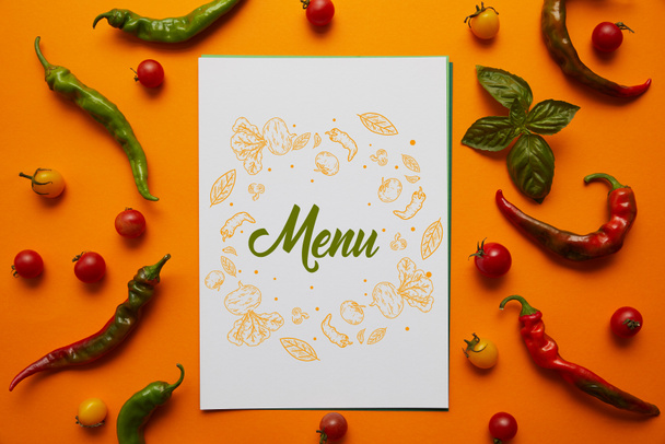 top view of card with "menu" lettering and fresh tomatoes with basil and peppers on orange - Φωτογραφία, εικόνα