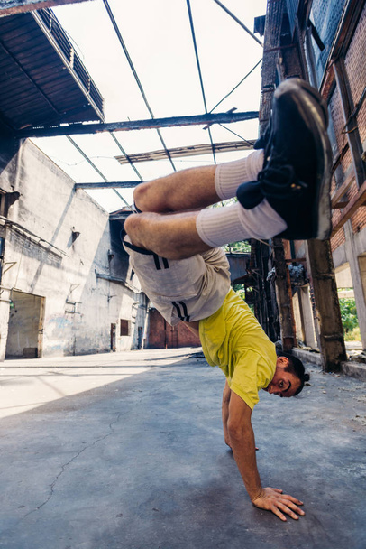 Homem desportivo mantém um equilíbrio no chão com uma mão
 - Foto, Imagem