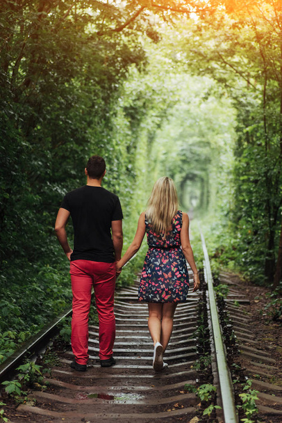 Loving couple in a tunnel of green trees on railroad. - Valokuva, kuva