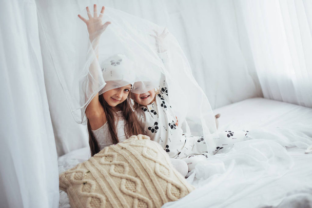 Children in soft warm pajamas playing in bed - Fotografie, Obrázek