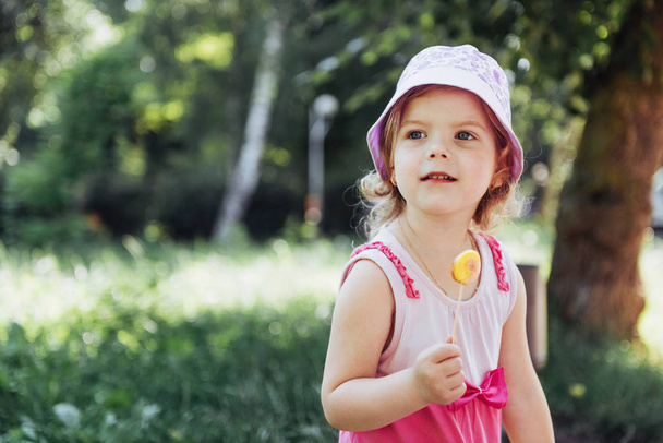 Funny child with candy lollipop, happy little girl eating big sugar lollipop, kid eat sweets. - Φωτογραφία, εικόνα