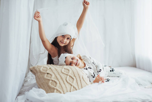 Children in soft warm pajamas playing in bed - Valokuva, kuva
