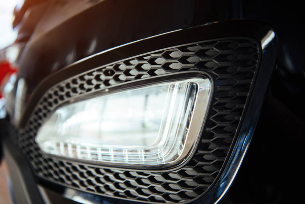 The headlights and the hood of a black sports car. - 写真・画像