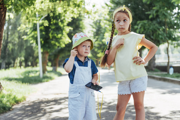 Cute girl and boy listening to music through headphones on the street. - Photo, Image