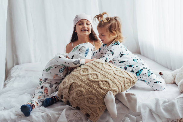 Children in soft warm pajamas playing in bed - Zdjęcie, obraz