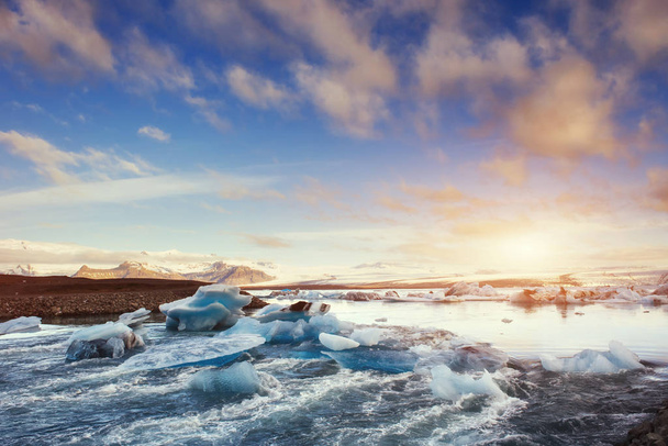 Icebergs in the glacial lake with a mountain in the south of Iceland at sunset. Jokulsarlon - 写真・画像