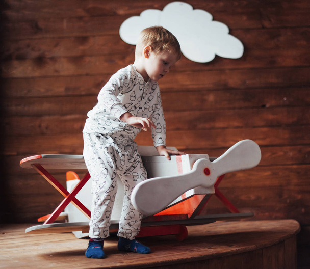 Happy kid playing with wooden airplane against. Childhood. Fantasy, imagination. Holiday - Valokuva, kuva