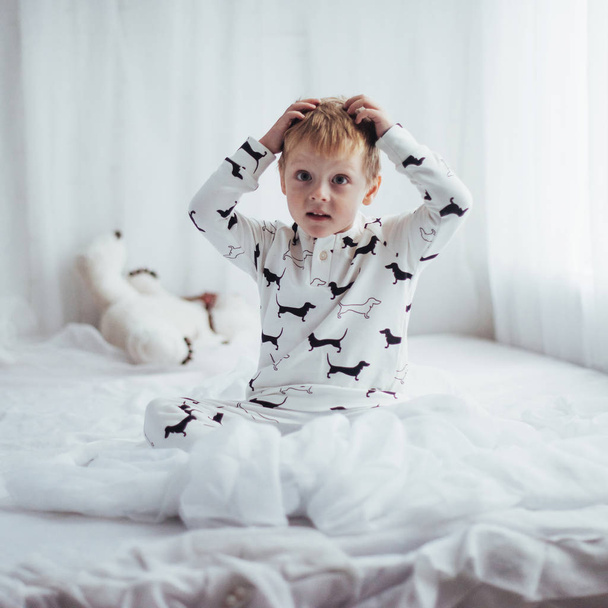 Child in soft warm pajama playing in bed - Valokuva, kuva