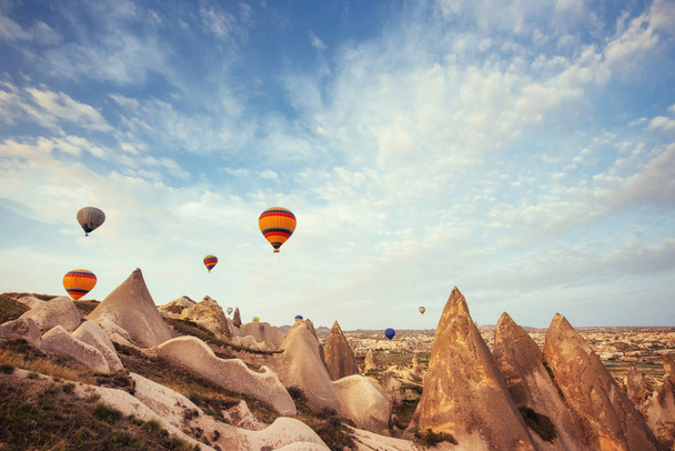 Hot air balloon flying over rock landscape at Cappadocia Turkey. Cappadocia with its valley, ravine, hills, located between the volcanic mountains in Goreme National Park. - Fotoğraf, Görsel