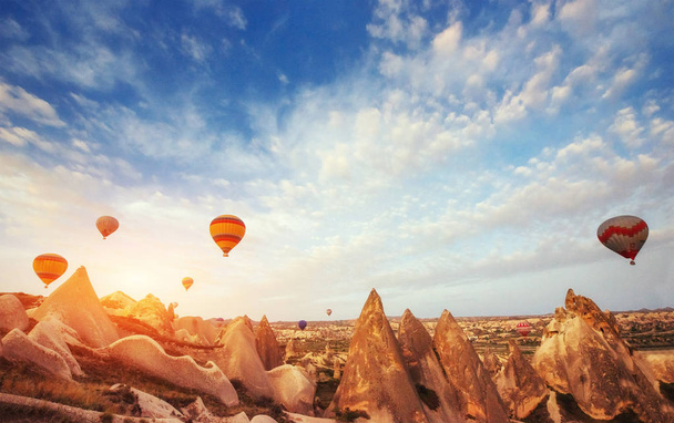Hot air balloon flying over rock landscape at Turkey. Cappadocia with its valley, ravine, hills, located between the volcanic mountains in Goreme National Park. - Photo, image