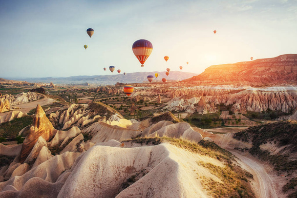Colorful hot air balloons flying over Red valley at Cappadocia, Anatolia, Turkey. Volcanic mountains in Goreme national park. - Photo, image