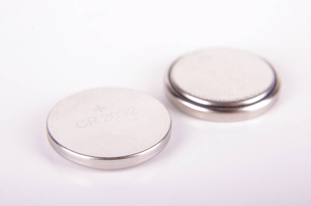 Крошечная кнопка батареи CR2032 с обеих сторон изолированы на белом фоне
 - Фото, изображение