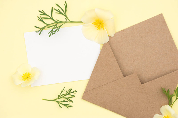 Umschlag aus Kraftpapier mit einer leeren Botschaft und schönen gelben Blumen - Foto, Bild