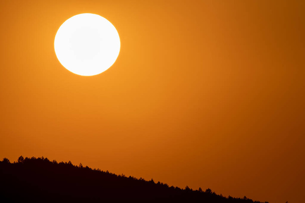 オレンジ色の空と山を夕暮れ時に大きな太陽円 - 写真・画像
