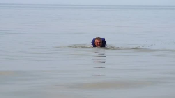 Człowiek sobie niebieski kurtka ratownicza, unoszące się na brzegu - Materiał filmowy, wideo