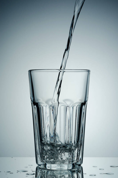 Water flows into the glass. Concept: the content. - Foto, afbeelding