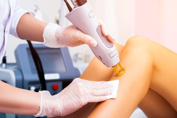 Close-up of a female cosmetologist in a medical coat making a young woman  a procedure laser hair removal for leg. Cosmetology, ionization, diamond procedures. - Fotó, kép