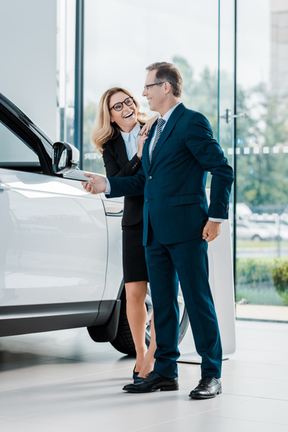 cheerful business couple looking for new automobile in dealership salon - Foto, immagini